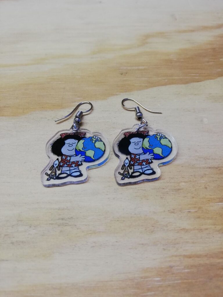 Fotografía de par de aretes "Mafalda geógrafa". Precio: $75 MXN Dimensiones de colgante: 2.5 x 2.5 cm. Material: Acrílico Categoría: Nuevo