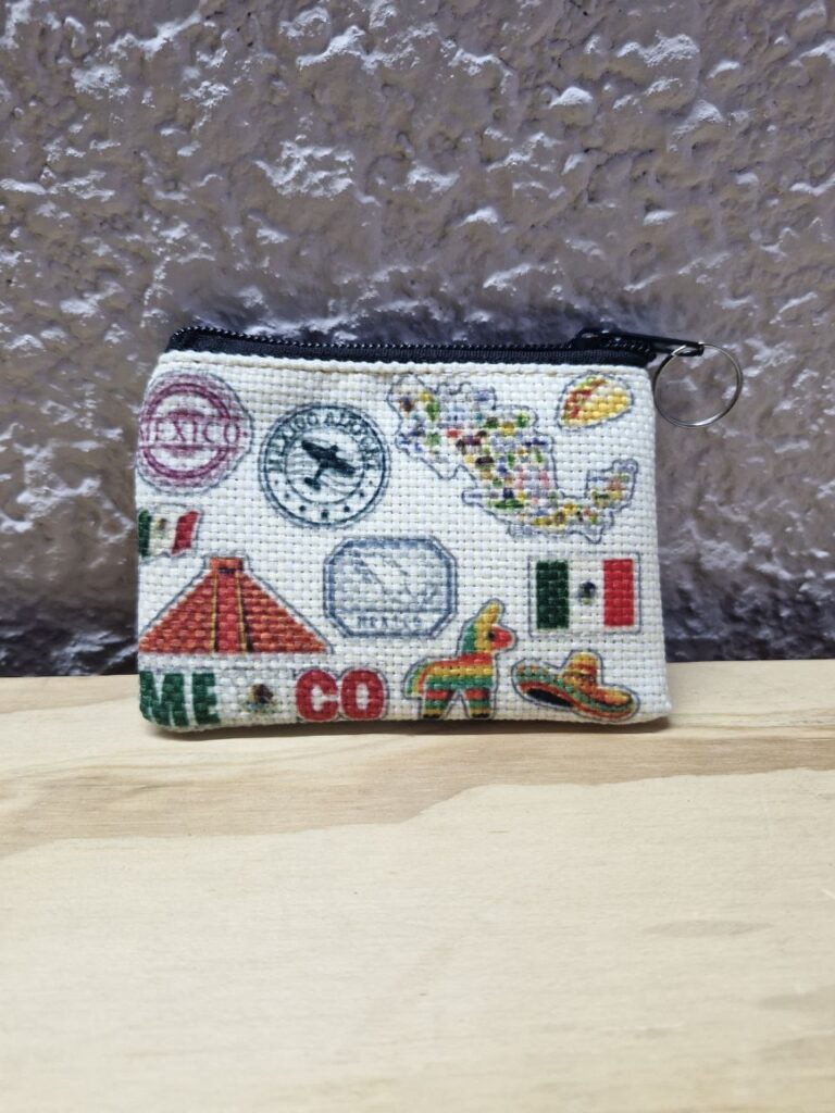 Fotografía de frente de monedero México Sellos. Precio: $20 MXN Dimensiones: 11 x 9 centímetros Material: Yute plástico Color de base: Blanco Tipo de cierre: Plástico con carrito metálico Forro: Negro Categoría: Nuevo
