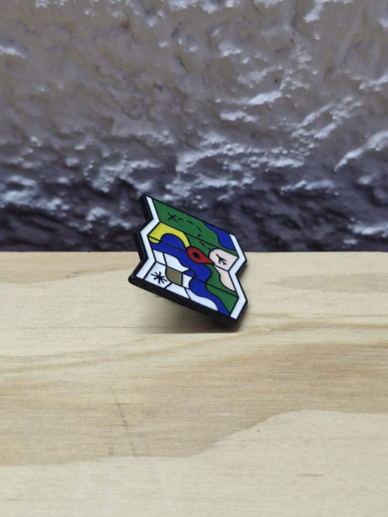 Fotografía de costado de Pin Mapa Precio: $100 MXN Dimensiones: Alto 2.4 cm., Ancho 2.3 cm., Grueso con broche puesto 0.9 cm. Material: Metal con policromía Color base: Negro Tipo de broche: Mariposa de metal Categoría: Nuevo