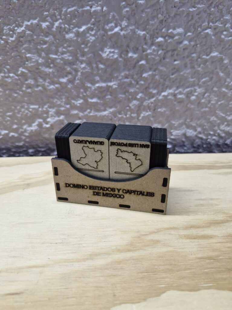 Fotografía de dominó de estados y capitales de México. Precio: $50 MXN Dimensiones: Caja llena: 6 cm. por 9 cm. por 3.8 cm.; Ficha: 0.25 cm. por 3 cm. por 5.5 cm. Color: Frente: Plateado; Detrás: Marrón oscuro Material: Madera industrializada Grabado y cortado con láser Idioma: Español Categoría: Nuevo