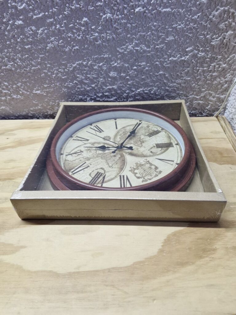 Fotografía de frente de reloj para pared de mapamundi en su caja. Precio: $240 MXN Dimensiones aproximadas: Diámetro 28 cm., Fondo 4.5 cm. Color: Marrón Materiales: Plástico y cristal Funciona con una pila AA de 1.5 Vcc Categoría: Nuevo