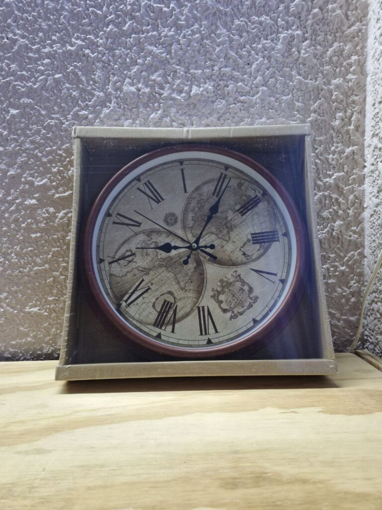 Fotografía de frente de reloj para pared de mapamundi en su caja. Precio: $240 MXN Dimensiones aproximadas: Diámetro 28 cm., Fondo 4.5 cm. Color: Marrón Materiales: Plástico y cristal Funciona con una pila AA de 1.5 Vcc Categoría: Nuevo